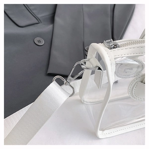 Detail einer transparenten PVC-Umhängetasche mit weißem Lederbesatz und Silberbeschlägen