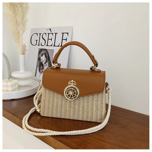 Detail of straw and leather patchwork handbag with gold clasp on wooden table