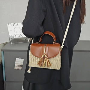 Detail of fashion straw crossbody bag featuring leather flap and woven rope shoulder strap