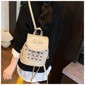 Dettaglio mini zaino beige con pizzo a cuore, fiocco decorativo e catene metalliche