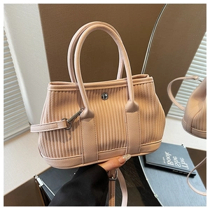 Detail of light pink pleated bucket bag featuring metallic buckle and dual handles