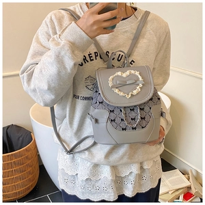 Détail du mini sac à dos gris avec dentelle coeur, noeud et panneau à carreaux noir et blanc