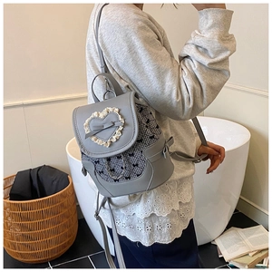 Détail d'un sac à dos en cuir PU gris avec cœur en dentelle blanche et nœud sur mannequin