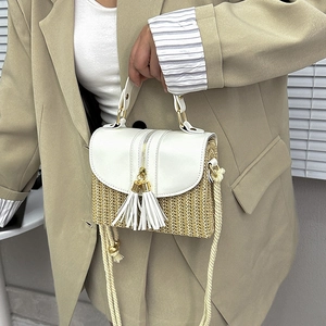 Detail of straw woven handbag featuring white PU flap and stylish tassel zipper puller