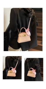 Détail d'un sac à main rose pâle gaufré croco avec fermoir doré et nœud en soie