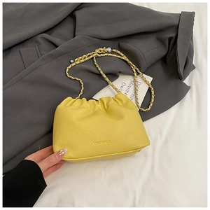 Detail of yellow lychee texture cloud bag featuring gold chain strap and brand logo