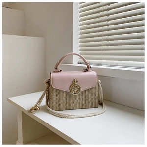 Detail shot of the woven straw texture and gold clasp on a pink leather crossbody bag
