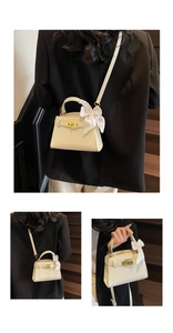 Détail du petit sac crème motif crocodile avec fermoir doré et ruban sur la poignée