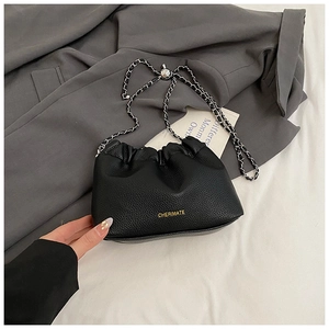 Detail of lychee pattern leather crossbody bag with silver chain and pleated drawstring