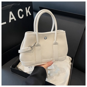 Detail of cream corduroy bucket bag texture with silver metal buckle and dual handles