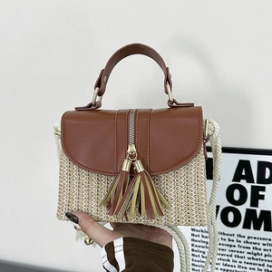 Detail of straw woven bag featuring brown leather trim, golden hardware, and tassels