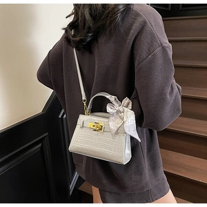 Détail du sac Kelly gris à motif crocodile avec foulard en soie et boucle dorée