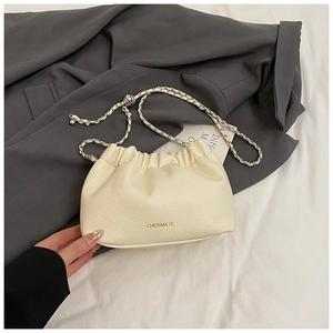 Detail of lychee pattern leather and gold metal chain on a beige pleated cloud bag