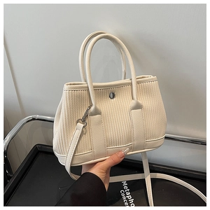 Close-up of cream pleated bucket bag with vertical texture and adjustable shoulder strap