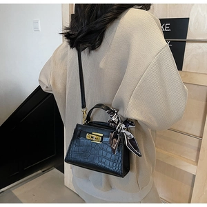 Détail du sac à main noir texture crocodile avec fermoir doré et foulard en soie