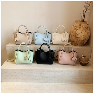 Detail view of multi-color litchi grain tote bags with cute elephant charms on stone steps