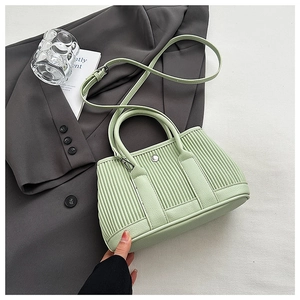 Detail of light green pleated leather bucket bag with top handle and adjustable strap