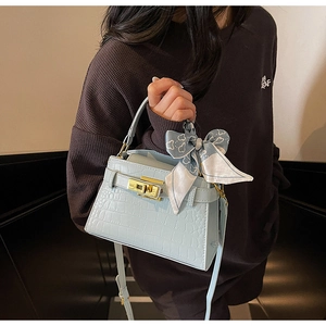 Détail du sac à main bleu clair effet croco avec fermoir tournant doré et foulard en soie