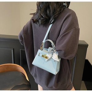Détail du sac bleu clair à motif crocodile avec foulard en soie porté par un mannequin