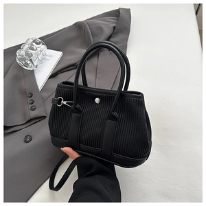 Detail of black corduroy bucket bag showing silver metal buckle and leather strap