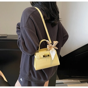 Gros plan sur un sac Kelly jaune à motif crocodile avec foulard en soie et fermoir doré