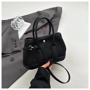 Detail of black corduroy tote bag showing fine ribbed texture and silver metal hardware