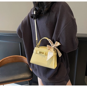 Détail de la texture crocodile et du fermoir doré sur ce petit sac à main jaune