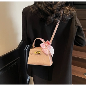 Détail du mini sac rose motif crocodile avec foulard sur la poignée et fermoir doré