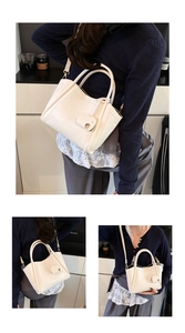 Detail view of cream textured bucket bag featuring a cute elephant charm and thin strap