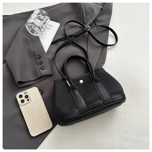 Detail of black pleated bucket bag showing lychee grain leather base and silver buckle closure
