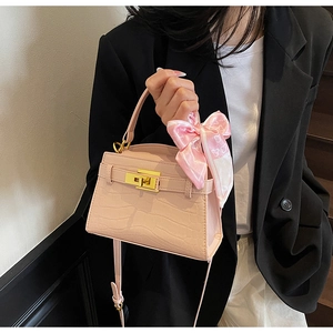 Sac rose à motif crocodile avec fermoir doré et foulard en soie sur l'anse