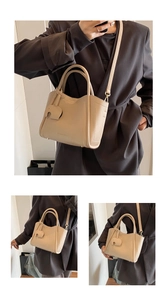Macro detail of beige lychee textured leather bag with elephant charm and brand logo
