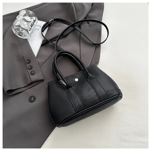 Detail of black pebbled leather bucket bag with silver buckle on a grey blazer