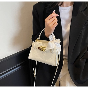 Détail du sac à main crème effet crocodile avec boucle dorée et ruban en satin