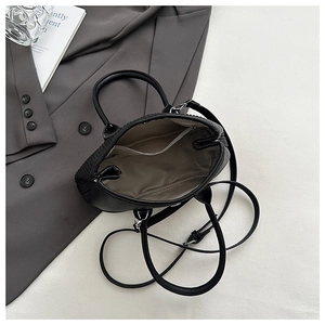 Top view of black lychee leather bucket bag interior with light gray lining and zipper pocket