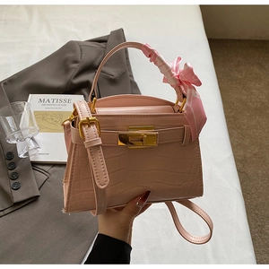 Détail d'un sac à main rose texture crocodile avec foulard en soie et fermoir doré