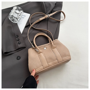 Macro view of beige pleated bucket bag with vertical texture and metal buckle detail