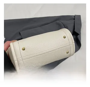 Detail view of white pebbled leather bag base with four protective gold metal feet studs