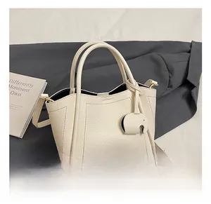 Detail of cream leather bucket bag with litchi texture and cute elephant charm