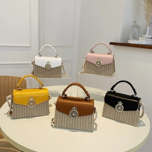 Straw woven square crossbody bags with crown lock in five vibrant colors displayed on table