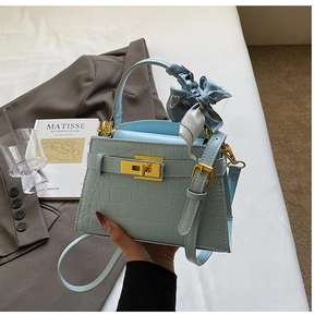 Détail du sac Kelly bleu clair à motif croco avec fermoir doré et foulard en soie