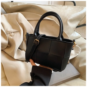 Detail of black woven leather handbag showing large grid pattern and golden strap buckle