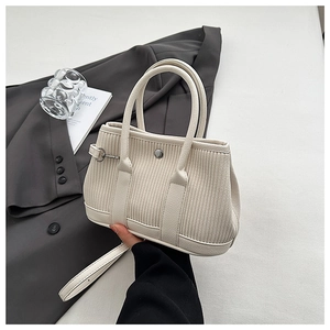 Close-up of pleated beige bucket bag texture with metal buckle and shoulder strap detail