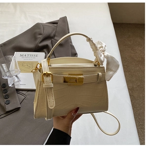 Détail du sac à main crème effet crocodile avec fermoir doré et ruban de soie élégant