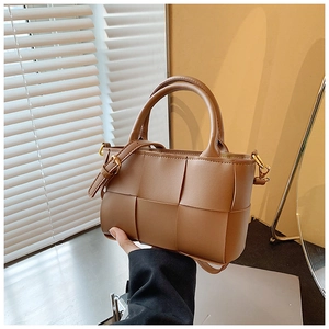 Detailed view of caramel brown woven leather crossbody bag with rounded handle and strap