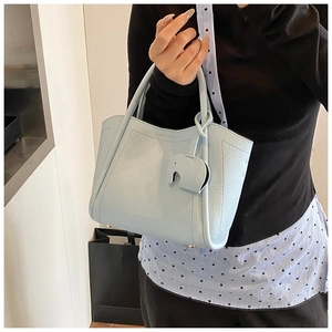 Close-up of light blue lychee grain leather bucket bag with cute elephant charm