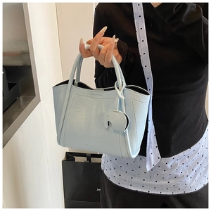 Detail of light blue pebble leather tote bag with elephant charm and dual handles
