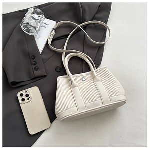 Detail of beige pleated bucket bag with metallic magnetic buckle and shoulder strap