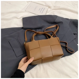 Detailed view of brown woven leather texture on small square bag with shoulder strap
