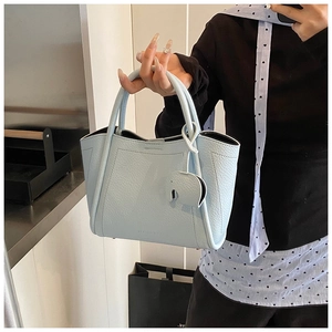 Close-up of light blue pebble grain leather bucket bag with cute elephant charm